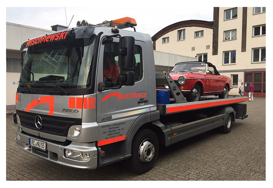 Ein Abschleppwagen hebt ein Elektroauto mithilfe eines Krans von einem Parkplatz